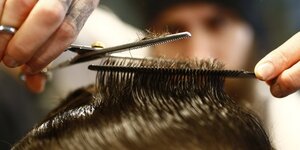 Coiffeur vellios se concentre sur le coiffage d'un client dans son salon de coiffure de torreto a francfort