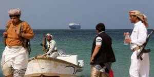 Des hommes armés se tiennent sur la plage alors que le navire commercial Galaxy Leader, saisi par les Houthis du Yémen le mois dernier, est ancré au large d'al-Salif.