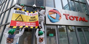 Des militants d'Attac accrochent une bannire  la faade de l'immeuble Total