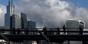 Des personnes marchent pres du millenium bridge avec le quartier financier de la city de londres derriere